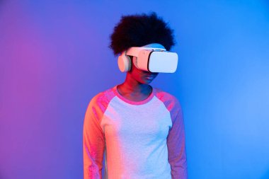 Profil, VR gözlük takan genç ve güzel Afrikalıların mavi ve pembe neon ışıklı arkaplanda izole olduğunu düşünüyor. Teknoloji ve dijital yenilik 3 boyutlu hologram gramında. Entrika.