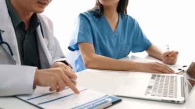 Hastane masasında birlikte çalışan ve tıbbi tedavi planlayan çeşitli profesyonel sağlık görevlileri. Takım çalışması başarılı hastalıklara ve hastalıklara yol açar. Ağır çekim. Katı.