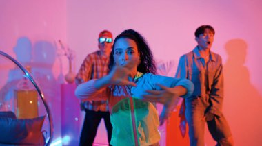 Çekici mutlu dansçı kameraya bakarken zeki kadın neon ışıkla kafiyeli hareket ediyor. Profesyonel İspanyol şarkıcı çeşitli arkadaşlarıyla renkli kıyafetler giyerken break dans yapıyor. Mutluluk.