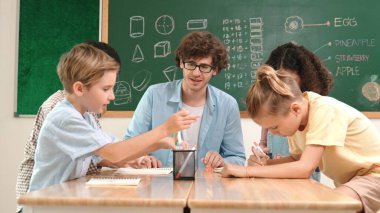 Zeki öğretmen, çeşitli çocuklar sınıf çalışması yapmak için birlikte çalışırken farklı çocukların zihin haritası çizdiği fikri açıklıyor. Çekici eğitmen öğretmek ve çalışmak hakkında konuşmak. Pedagoji.