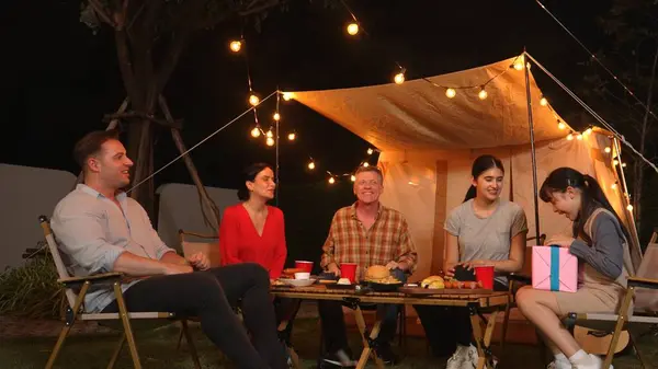 stock image Family together celebrate anniversary in garden. Senior give gift to granddaughter. Outdoor camping activity to relax with relatives, spend time with multigeneration cross generation gap. Divergence.