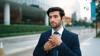 Profesyonel iş adamı yolda yürürken kravatı ayarlar. Yönetici şehre bakarken takım elbise giyiyor. Yatırımcı görüşmeye gitmeden önce kendini kontrol etmiş. Arka plan bulanık. Sevinçli..