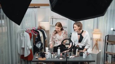 Etkilenen iki ortak canlı yayında video görüntülerini çekiyor makyaj malzemesi prim sosyal medya veya blog. Kozmetik stüdyosu ışıklandırmalı mutlu genç kız çevrimiçi pazarlama oturumu yayını için..