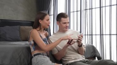 Genç çift, kredi kartıyla ödemek için internet üzerinden ödeme uygulaması ve dijital cüzdan kullanarak yatak odasında oturuyor. Mobil internet üzerinden alışveriş ve modern alımlar. Düzenle