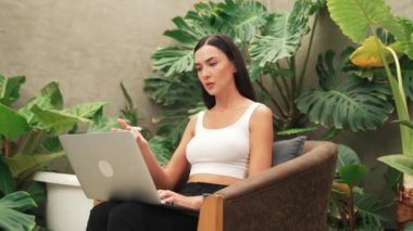 Stresli kadın, yeşillik arka planında internet üzerinden çalışırken yorgun ve hayal kırıklığına uğramış hissediyor. Bunaltıcı ve zorlu uzak çalışma görevleri. Blithe
