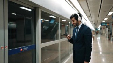 Proje yöneticisi, tren istasyonunda cep telefonu ve arama ekibi tutarken kulaklık takıyor. Zeki iş adamı bulanık bir geçmişi olan treni beklerken rahatlatıcı müzik dinliyor. Sevinçli..