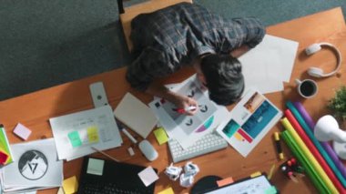 Toplantıda tasarımcı yazma ve logo grafiği tasarlamanın en üst görünümü. Renkli paletler üzerinde çalışan iş adamlarının yakınlaşması ve masaya kağıt ve ekipman ile yapışkan notlar yazmak. Sempozyum.