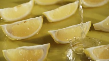 Sarı arka planda suya düşen limon dilimlerinin yukarıdan görünüşü. Taze limon dilimlenmiş, ayrı sarı arka planda su dökülüp sıçrama yapılan yere yakın durun. Citrus tazeliği. Pabulum.