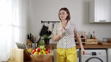 Enerjik beyaz anne kahvaltı için salata pişirirken ve yemek pişirirken elinde kepçeyle şarkı söylüyor. Sağlıklı yemek yapmaya hazırlanırken müziğe yönelen mutlu ev sahibi. Pedagoji.