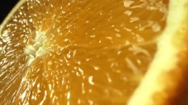 Portakal diliminin bir makrografi görüntüsü, parlak, izole edilmiş bir arkaplan üzerine yerleştirilmiş, narenciye cazibesinin görsel bir başyapıtı olarak gözler önüne seriliyor. Siyah arkaplanlı bir dilim portakal. Geliştirilebilir.