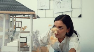 Genç, beyaz, güzel mimar mühendisi ev modelini ev inşaatını teftiş etmek ve sorunu modern ofisteki toplantı masasında çözmek için hata noktasını kontrol etmek üzere çeviriyor. - Yakın çekim. Tertemiz..