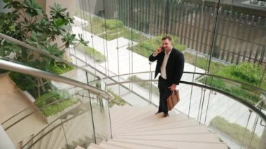 Kafkas işadamı akıllı telefon kullanarak müdürü arıyor ve mali raporları tartışıyor. Erkek lider, modern binada merdivenlerde dururken telefonla pazarlama ekibini konuşuyor. Urbane.
