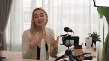 Sosyal medya için güzellik ve kozmetik video içeriği hazırlayan genç bir kadın. Güzellik blogcusu kameraya gülümserken seyircilere ve takipçilere güzellik bakımını gösteriyor. Blithe