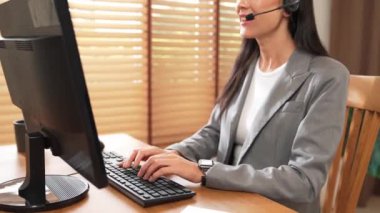 Kadın çağrı merkezi operatörü ya da müşteri hizmetleri çalışanı, müşteriye yardım etmek için kulaklıkla konuşurken çalışma alanı üzerinde çalışıyor. Profesyonel modern iş hizmeti. Blithe