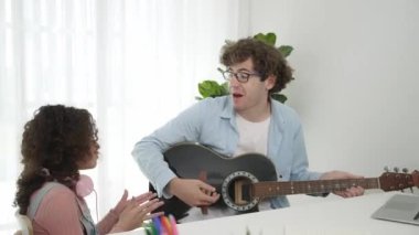 Beyaz bir baba, okul kızıyla müzik eşliğinde akustik şarkı ya da melodi eşliğinde dans etmeyi ve gülmeyi sever. Akıllı baba gitar çalarken neşeli kız dinliyor. Eğlence için. Pedagoji.