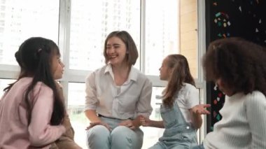 Öğretmen ve çeşitli öğrenciler sınıfta el ele tutuşuyorlar. Genç eğitmen ve çok kültürlü çocuklar tezahürat yapıyor ve teşvik ediyor. Birlik, sevgi, işbirliği, birlikte çalışma. Etkinlik.