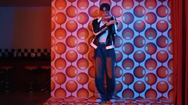 Asyalı break dansçı serbest stile geçiyor ve balon arka planlı kameraya bakıyor. Profesyonel hippi gündelik kıyafet giyer ve gözlük takar. Mutluluk.