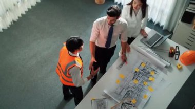 Proje yöneticisi ve inşaat mühendisinin elinde dizüstü bilgisayarla fikirleri mimara anlatırken üst düzey görüntüsü. Akıllı iş adamlarının bina inşaatı hakkında konuştuğu ve beyin fırtınası yaptığı hava görüntüsü. Hizalama.