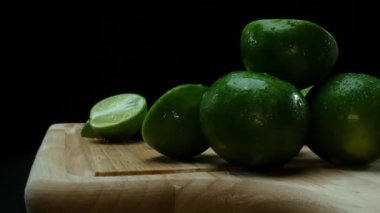 Yakın plan, canlı bir dilim taze kireç kırsal bir ahşap kesme tahtasının üzerinde duruyor. Tazelik ve canlılık yayıyor. Kesme tahtasına konmuş yeşil limon diliminin yarı saydam zarları. Geliştirilebilir.
