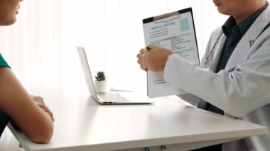 Klinikteki ya da hastane ofisindeki doktor randevusuna katılan hasta, tıbbi tedavi seçeneklerini tartışıyor ve muayene sonuçlarını ya da hastalıkla ilgili tıbbi kayıtları açıklıyor. Ağır çekim. Katı.