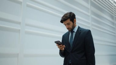 Yetenekli yönetici, iş arkadaşıyla proje hakkında konuşmak için telefon görüşmesi yapıyor. Yakışıklı erkek lider, ayakta durup kameraya bakarken satış hakkında konuşmak ve rapor vermek için iş ekibini arıyor. Sevinçli..