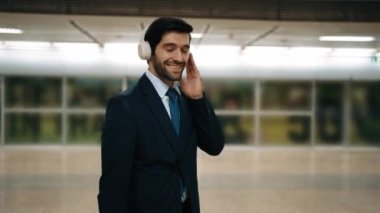 İş adamı, peronda arka planı bulanık bir şekilde tren beklerken kulaklıktan müzik dinliyor. Proje yöneticisi cep telefonu tutarken dinlenme sesi dinlemeyi sever. Sevinçli..