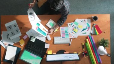 Akıllı iş adamının logo grafiği tasarlarken renk paletleri seçmesinin üst görünümü. Profesyonel iç mimar tasarımının hava görünümü ve renk paletleri kullanarak renk temasını seçin. Sempozyum.