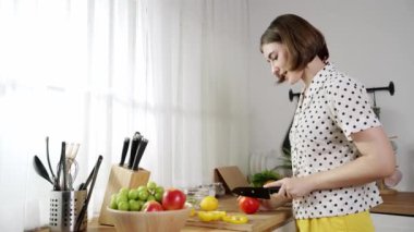 Çekici beyaz anne salata yapmak için taze sebze doğruyor. Mutlu enerjik akıllı anne kahvaltıda sağlıklı yemek pişirirken modern mutfakta çalışıyor. Yemek hazırlama konsepti. Pedagoji.