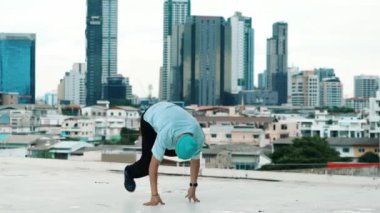 Profesyonel beyaz dansçı, şehir ya da şehirle çatıda sokak dansı yapıyor. Genç adamın sokak dansı yaparken dondurucu poz vermesi. Açık hava sporu 2024 hiphop..