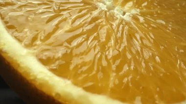 Portakal diliminin bir makrografi görüntüsü, parlak, izole edilmiş bir arkaplan üzerine yerleştirilmiş, narenciye cazibesinin görsel bir başyapıtı olarak gözler önüne seriliyor. Siyah arkaplanlı bir dilim portakal. Geliştirilebilir.