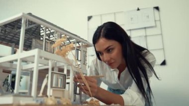 Genç, güzel ve zeki mühendisin yakın çekimleri modern ofiste duvarında taslak olan kalem kullanarak ev modelini ölçmeye odaklanıyor. Yaratıcı yaşam ve tasarım konsepti. Tertemiz..