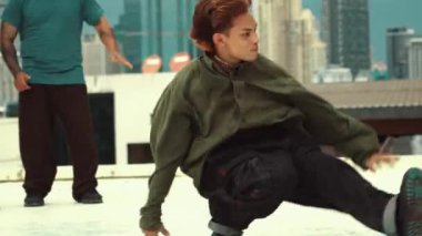 Profesyonel Asyalı sokak dansçısı çatıda çok kültürlü arkadaşlar dans ederken B boy dansı yapıyor. Genç modern dans grubu hip hop hareketi yapıyor. Tarz, moda, aksiyon. Açık hava sporu 2024 hiphop..