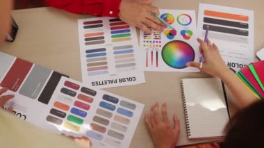 Üst görünüm yavaş çekim eli, grafik tasarımı için çalışan iki tasarımcının ya da tasarımcıdan yaratıcı kromatik konsültasyonda renk uygulaması arayan istemcinin masasının üzerinde. Değiştirilmiş