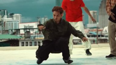 Profesyonel Asyalı sokak dansçısı çatıda çok kültürlü arkadaşlar dans ederken B boy dansı yapıyor. Genç modern dans grubu hip hop hareketi yapıyor. Tarz, moda, aksiyon. Açık hava sporu 2024 hiphop..