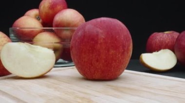 Elmaların makrografisi çeşitli şekillerde sergilenir: bütün, dilimlenmiş ve siyah arka planlı cam bir kase içinde. Her yakın çekim kesme tahtasındaki elmaların kırmızı renklerini yakalar. Geliştirilebilir.