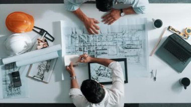 İnşaat mühendisinin bina tasarımını planlamak için birlikte çalıştığına dair üst düzey bir görüş. Yönetici planlar hakkında konuşurken ve tartışırken yetenekli mimar takımının yukarıdan görünüşü. Hizalama.