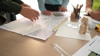 Mimari döküman, ölçüm araçları ve ahşap blokların modern ofiste etrafa saçıldığı masa üzerine planlar yapma konusunda akıllı mimar ve güvenlik mühendisi tartışması. - Yakın çekim. Tanımlama.