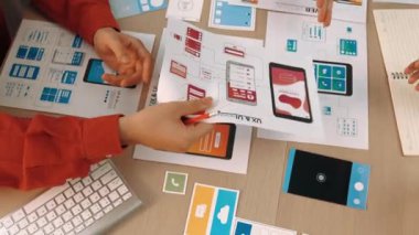 Mobil uygulama için kullanıcı arayüzü prototipini ofis çalışanlarına sunan harika bir şirket çalışanı. UX UI tasarımcısı kağıt üzerinde simge tasarımının işlevini açıklıyor. Sinerjik