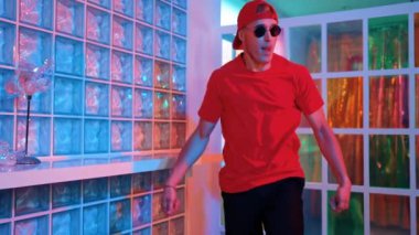 Komik break dansçı kameraya bakarken hiphop 'a doğru serbest adım atıyor. Çılgın mutlu hipster dans edip sokak dansı yaparken Led ışığında günlük kıyafet ve güneş gözlüğü takıyor. Mutluluk.
