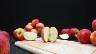 Elmaların makrografisi çeşitli şekillerde sergilenir: bütün, dilimlenmiş ve siyah arka planlı cam bir kase içinde. Her yakın çekim kesme tahtasındaki elmaların kırmızı renklerini yakalar. Geliştirilebilir.