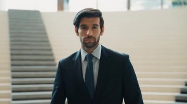 İş adamı kameraya bakarken kollarını kavuşturup arkasını dönüyor. Zeki, yakışıklı proje yöneticisi kameraya poz verirken kendine güvenen, arka planı bulanık bir şekilde merdivenlerde gülümsüyor. Sevinçli..