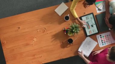 Renk paletinden renk seçmek için birlikte çalışan iş adamlarının üst düzey hava görüşü. İşadamı logo grafiğine bakarken pazarlama ekibine tablet kullanarak yönetici fikri sundu. Sempozyum.