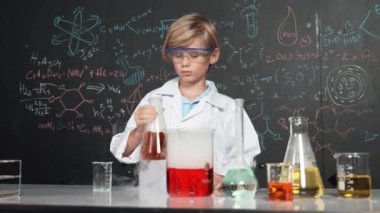 Akıllı çocuk, laboratuvar şişelerinde karışık kimyasal sıvıları dikkatlice inceler. Beyaz çocuk kimya dersi ya da BTMM fen dersinde bir deney yapmaya odaklan. Etkinlik.