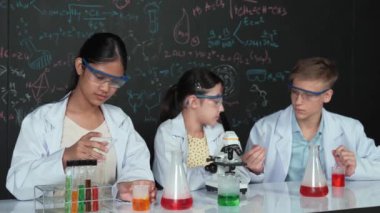 Akıllı genç kız kimya teorisi ile tahtayı dikkatlice incelerken mikroskop altında numune bırakıyor. Profesyonel bilim adamı tüpün içine kimyasal madde döker ve deney için hazırlanır. Öğretim