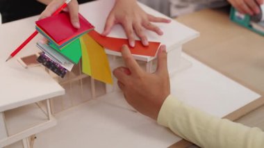 Mimari ekipman kullanarak yavaş çekim ev tasarımcısı bir plan çizerken, iç mimari tasarımcı da müşterilerin talebine göre renk örneklerinden uygun renkler seçiyor. Değiştirilmiş