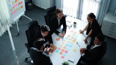 Proje yöneticisinin üst görünümü artan satış tablosunu sunarken, çeşitli gruplar başarılı bir projeyi kutlamak için el çırpıyor. Yatırımcı tahtaya yapışkan notlar koydu ya da pazarlama fikrini seçti. Müdürlük.