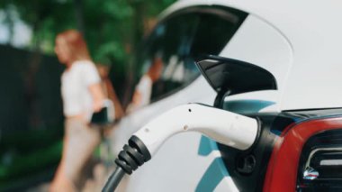Yavaş çekim odaklı EV elektrikli araba yeşil sürdürülebilir şehir açık hava bahçesinde şarj çift bulanık arka planı şehir elektrikli araç iç organları için temiz şarj edilebilir