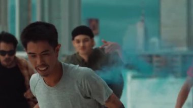 Bir grup çok kültürlü hippi çatıda işaret fişeği çalıyor. Zenci dumanı tutan çekici bir sokak dansçısı hip-hop müzik eşliğinde break dans yapıyor. Açık hava sporu 2024. Sokak dansı. hiphop.