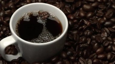 Kahve ya da kahve çekirdekli espresso manzarası. Taze kavrulmuş kahve çekirdeğini yakın çekimde ahşap masanın etrafına bir fincan americano ve aromatik akarsu ve tohum dumanı serpin. Geliştirilebilir.
