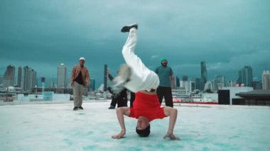 İspanyol hipster dansları şehrin mavi gökyüzü manzaralı çok kültürlü arkadaşlarıyla çevrili. Çatıda bir grup sokak dansçısı sahne alıyor. Aktif, eğlenceli, mutlu atmosfer. Açık hava sporu 2024 hiphop..